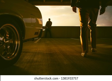 Drama And Cinematic 70s Shot Of A Silhouette Of A Man What A Jacket And Pants Walking From His El Camino Car Towards Someone Wearing A Brown Leather Jacket While Waiting In A Parking Garage