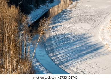 A dramatic aerial perspective of the Gauja river as it snakes through a winter woodland in Latvia