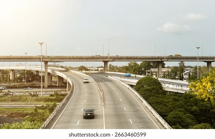 Dramatic aerial view of elevated roads and traffic junction in suburb area of Bangkok with beautiful view of countryside atmosphere during sunny day.
