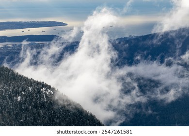 A dramatic aerial view of a mountainous landscape where clouds dance through snow-dusted evergreen forests. - Powered by Shutterstock