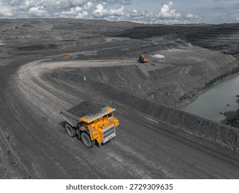 Dramatic aerial view of open pit coal mine with heavy machinery operations.