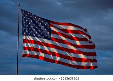 Dramatic American Flag flying high in front of a dark evening sky