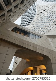 A dramatic angle of modern architecture, showing overlapping curved structures and a tower rising behind them.