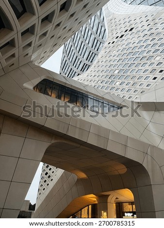 A dramatic angle of modern architecture, showing overlapping curved structures and a tower rising behind them.