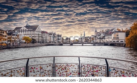 Dramatic autumn sunset paints the sky over Zurich's Old Town and Limmat river, viewed from the romantic Mühlesteg bridge adorned with countless love locks