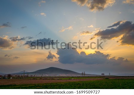 Dramatic black and red clouds with sunbeam over adacal hill at sunset, Emirdag, Afyonkarahisar, Turkey