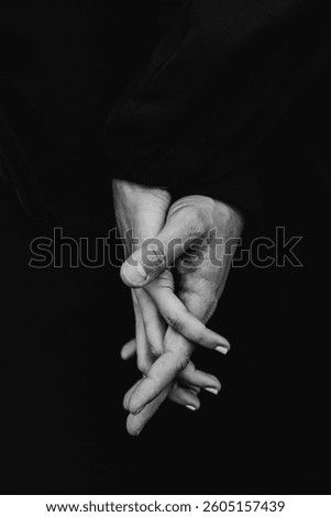 A dramatic black and white close-up, hand in hand, fingers intertwined in an intimate and emotional gesture 