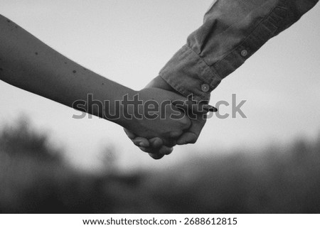 Dramatic black and white close-up of a man and woman holding hands against a soft, blurred background, representing love, emotional support, partnership, and deep connection.