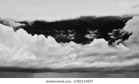 Dramatic black and white cloudscape texture. High contrast dark sky with bright fluffy cumulus clouds. Monochrome conceptual background for storm, mystery or moody atmosphere.
