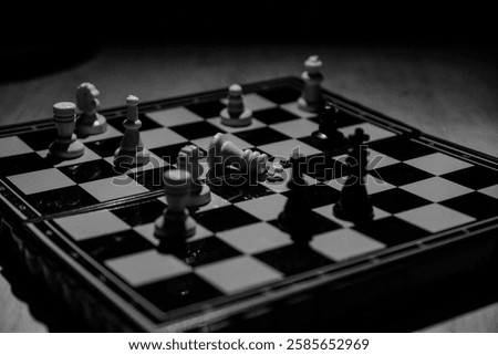 Dramatic black and white image of a chess game nearing its end, with the king fallen on the board. The composition conveys a sense of tension and finality, highlighting the strategic battle. Ideal for