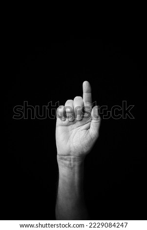 Dramatic black and white  image of a male hand fingerspelling the Fench sign language letter 'G', isolated against a dark background with copy space Stock fotó © 