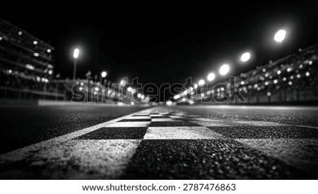 A dramatic black and white image of a race track finish line at night, illuminated by stadium lights, with grandstands visible.