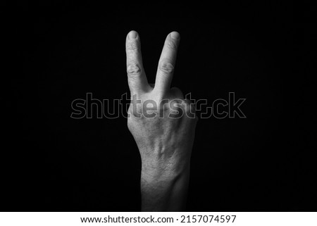 Dramatic black and white image of Reverse Victory Hand emoji isolated on black background