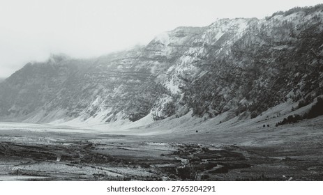 Dramatic black and white landscape of the distant steep, misty mountains at Mount Bromo