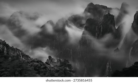 Dramatic black and white landscape features majestic rugged mountains enveloped in swirling mist and fog