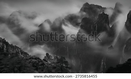 Dramatic black and white landscape features majestic rugged mountains enveloped in swirling mist and fog