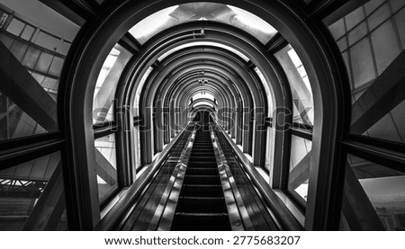 A dramatic black and white perspective of an escalator moving upwards within a modern, curved architectural structure creating a sense of depth and motion
