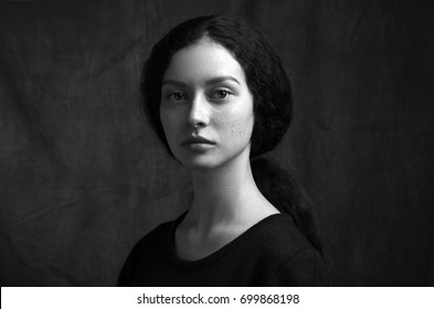 Dramatisches Schwarz-Weiß-Porträt eines schönen einsamen Mädchens mit Sommersprossen einzeln auf dunklem Hintergrund, Studioaufnahme
