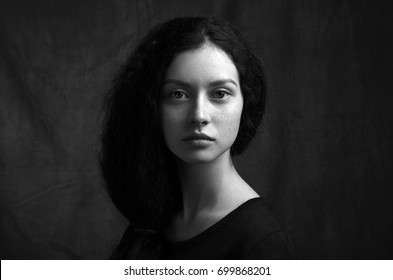 Dramatic Black And White Portrait Of A Beautiful Lonely Girl With Freckles Isolated On A Dark Background In Studio Shot