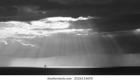 Dramatic Black and White Seascape with Sunlight Rays and Sailboat - Monochrome Ocean Photography, Nature’s Light Show, Serene Sea, Peaceful Sailing, Stormy Sky, Contrast in Nature - Powered by Shutterstock