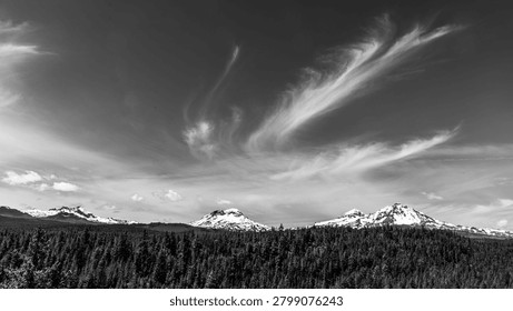 Dramatic black and white view of the central Oregon Cascade Range with wispy clouds in a dark sky