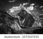 Dramatic black and white view of Half Dome rock formation in Yosemite National Park ; sky and puffy clouds in background