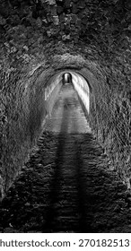 Dramatic black and white view of historic brick tunnel with strong leading lines and vanishing point