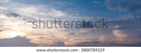 Dramatic blue cloudscape with sunlight breaking through layers of clouds in the evening sky