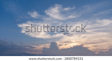 Dramatic blue cloudscape with sunlight breaking through layers of clouds in the evening sky