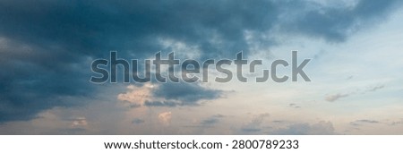 Dramatic blue cloudscape with sunlight breaking through layers of clouds in the evening sky