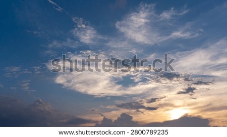 Dramatic blue cloudscape with sunlight breaking through layers of clouds in the evening sky