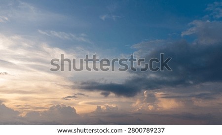 Dramatic blue cloudscape with sunlight breaking through layers of clouds in the evening sky