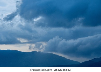 Dramatic blue and grey clouds loom over distant mountains, creating a moody and serene natural landscape.
