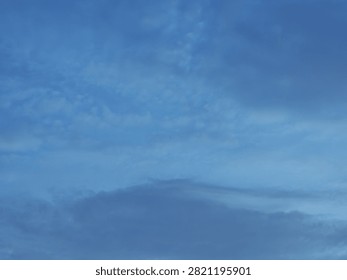 A dramatic blue hour sky captured during twilight, featuring a deep indigo backdrop layered with thick, dark clouds. The heavy cloud cover appears dense and sombre, creating a strong contrast against the cool blue tones of the fading daylight. This atmospheric scene is characteristic of the evening transition known as the “blue hour,” offering a moody and cinematic skyline.