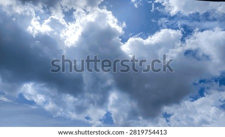 Dramatic blue sky background with thick dark clouds and bright sunlight breaking through the atmosphere.