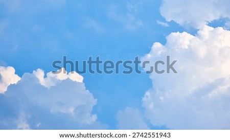 Dramatic blue sky background with white fluffy cumulus clouds and bright sun rays shining through. Beautifu s natural light.