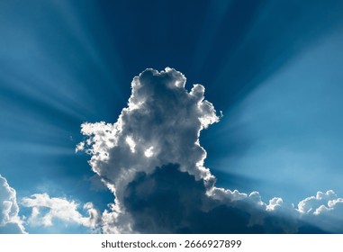 Dramatic blue sky with backlit clouds and sunbeams in late afternoon.