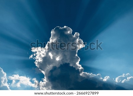 Dramatic blue sky with backlit clouds and sunbeams in late afternoon.