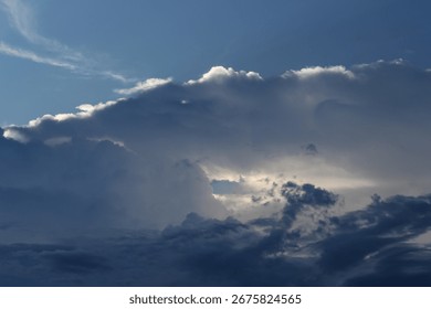 A dramatic blue sky with dark clouds and sunlight peeking through. A dramatic atmosphere before a storm.