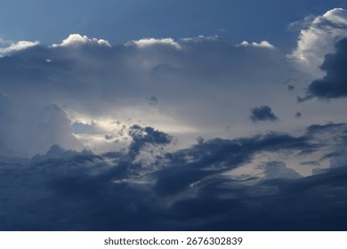 A dramatic blue sky with dark clouds and sunlight peeking through. A dramatic atmosphere before a storm.