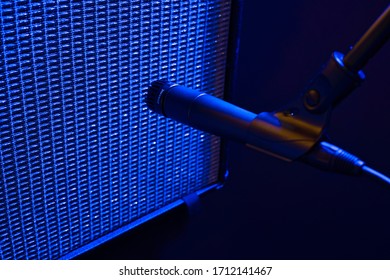 Dramatic Blue Stage Light Illuminates a Dynamic Style Microphone Placed in Front of a Vintage Guitar Amplifier