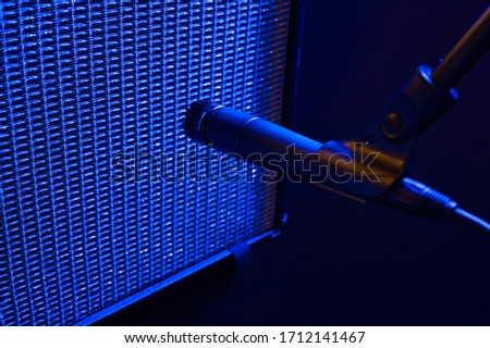 Dramatic Blue Stage Light Illuminates a Dynamic Style Microphone Placed in Front of a Vintage Guitar Amplifier Stock photo © 