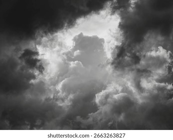 Dramatic break in stormy cumulus clouds on a summer evening in Florida. (Black and white.) Motifs of change and uncertainty, yin and yang, the butterfly effect and predictability in chaos theory.