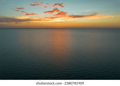 Dramatic bright red sky at ocean sunset, soft evening clouds over sea dark water