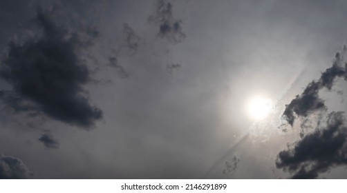 Dramatic bright sunlight shining over the dark grey sky. Beautiful silhouette cloudy scene, cloudscape floating overhead before rain, depth of field. Rainy clouds in the dull evening. Nature overhead.