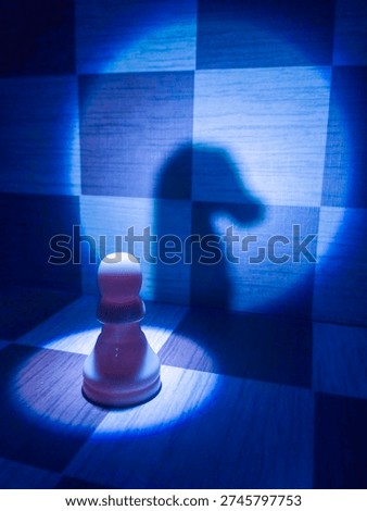 A dramatic chess scene captured in a cool blue tone, featuring a single pawn illuminated under a focused spotlight. The strong contrast casts a knight-shaped shadow on the chessboard wall, symbolizing hidden potential, ambition, and the psychological tension between identity and perception.