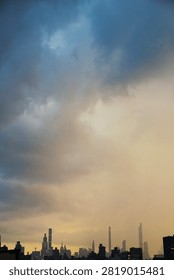 A dramatic cityscape view featuring a high-contrast stormy sky with deep blue clouds blending into a vibrant golden horizon, creating a moody atmosphere.
