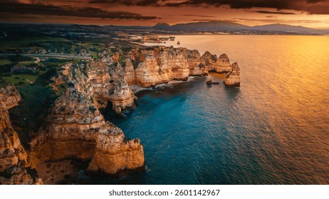 Dramatic cliffs at Ponta da Piedade, Algarve, Portugal, glowing in the golden hues of sunset. The Atlantic Ocean reflects vibrant colors, creating a breathtaking coastal view perfect for travel photog