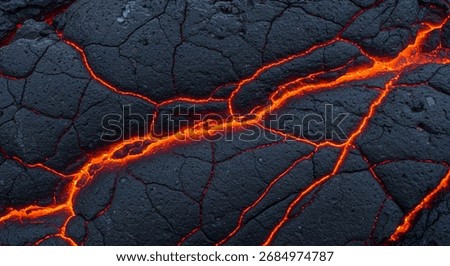 A dramatic close up of glowing orange lava seeping through the dark, cracked crust of solidified basalt rock, creating a powerful and abstract natural texture.
