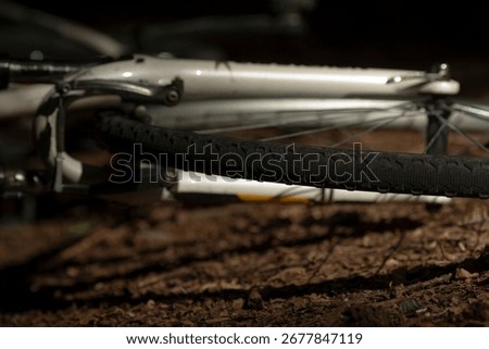 A dramatic close-up of bicycle wheels resting on the ground, captured at night with a focus on texture and detail, showcasing the unique patterns of the tire.